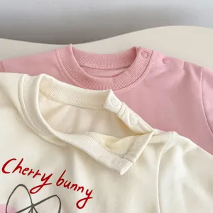 Détail de l'encolure bébé avec boutons-pression et imprimé lapin cerise en coton doux