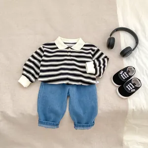 Flat lay of boys striped polo top and casual denim pants with accessory details