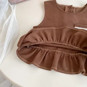 Detailed view of dark brown cotton vest with ruffled hem and delicate overlock stitching