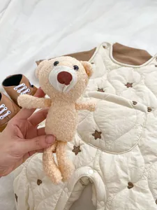 Detail of baby quilted overalls with brown star embroidery and matching teddy bear plush