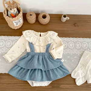 Baby girl fall outfit featuring beige ruffled top and blue corduroy suspender skirt set