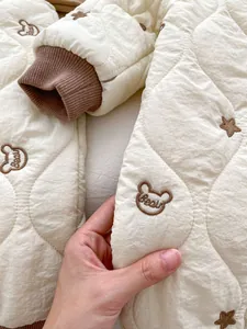 Close-up of quilted baby romper fabric with cute bear embroidery and ribbed cuffs