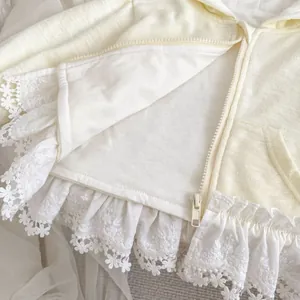 Détail de gilet pour bébé avec bordure en dentelle fleurie et fermeture éclair