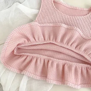 Detailed macro shot of pink baby romper with lotus leaf ruffles and waffle texture