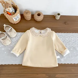 Détail du t-shirt bébé à manches longues crème avec col en dentelle et étiquette