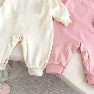 Vue détaillée de barboteuses en coton pour bébé rose et crème avec poignets côtelés