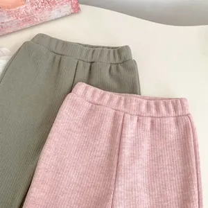 Details van geribbelde gebreide textuur en elastische hoge taille op groene en roze broek