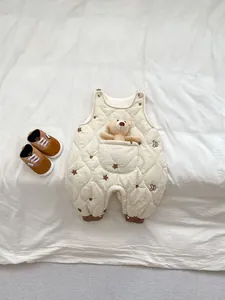 Detail of baby quilted romper featuring brown star embroidery and a bear toy in pocket