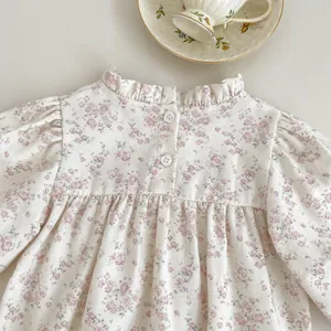 Detail of floral baby girl romper with ruffle collar and puff sleeves on white background