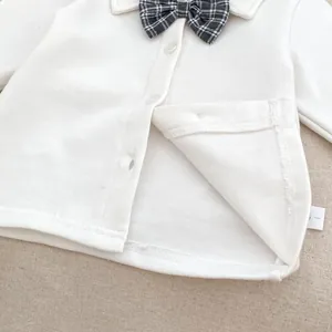 Close-up of baby white cotton shirt collar with a grey plaid bow tie and white buttons