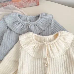 Detail einer gestrickten Babyjacke mit Rüschenkragen und vertikaler Rippenstruktur
