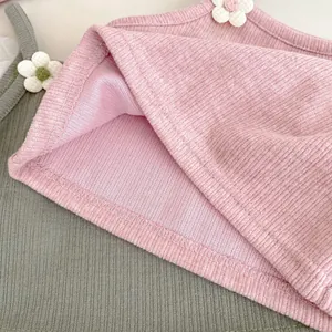 Detail van geribbelde gebreide stof met 3D-bloemen op roze en grijze kinderkleding