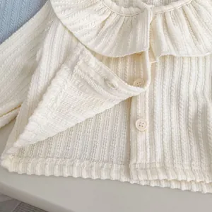 Detailansicht der cremeweißen Strickjacke mit elegantem Rüschenkragen und Strickstruktur