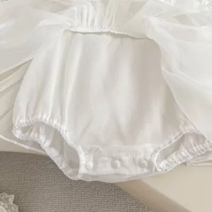 Detail of white cotton romper with snap buttons and layered tulle for baby girls
