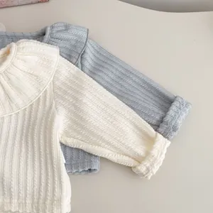 Detail eines Baby-Strickstramplers mit Rüschenkragen und Rippstruktur in Creme und Blau