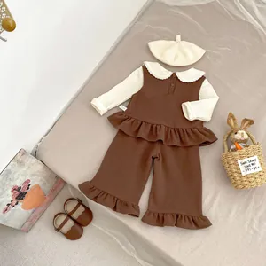 Detail of girls' brown ruffled vest and trousers with a white frill collar long sleeve shirt