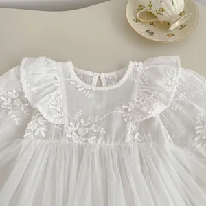 Close-up of white baby princess dress featuring floral embroidery and lace mesh details