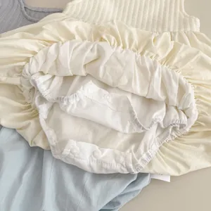 Detail eines Baby-Strampler-Kleides mit Strickoberteil und praktischen Druckknöpfen im Schritt