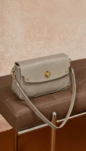 Gros plan sur le sac en cuir gris avec fermoir en métal doré et couture blanche