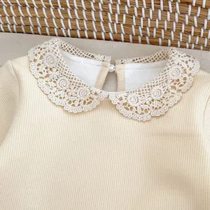 Détail du body bébé avec col Claudine en dentelle fleurie et tissu en maille côtelée