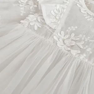 Detailed view of white baby princess dress featuring fine floral embroidery and soft tulle fabric
