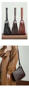 Detailed view of pebbled leather handbags in black and brown with wide shoulder straps