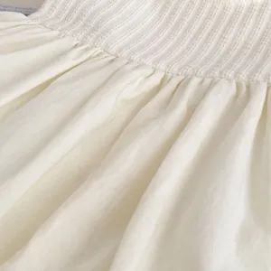 Detail der elastischen Smock-Taille und des weichen, gefalteten Baumwollstoffes des Bodysuits