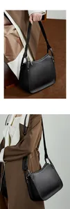 Detail of black pebbled leather texture and silver zipper hardware on minimalist handbag