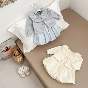 Detailansicht der Strickjacke und des Blumen-Stramplers für Babys mit Etikett Gr. 66