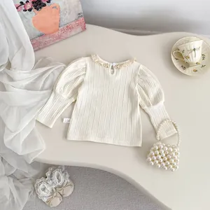 Detail van de kanten kraag en geribbelde textuur op deze witte kinder top met lange mouwen
