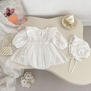Detail of white infant dress with floral embroidery, ruffles and layered mesh skirt