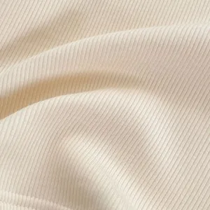 Gros plan détaillé sur la texture du tricot côtelé doux couleur crème pour bébé