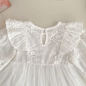 Close-up of white baby girl bodysuit with floral embroidery and ruffle sleeves