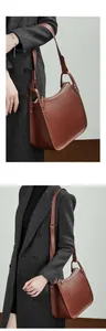 Detail of brown pebbled leather shoulder bag with silver rivets and adjustable strap