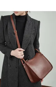 Detailed close-up of brown pebbled leather texture and metal rivets on crossbody bag