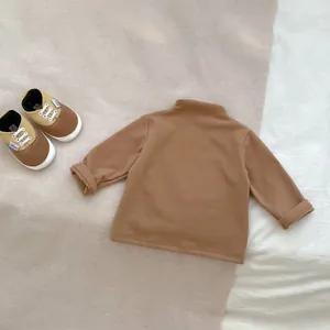 Close-up of soft brown high-neck baby shirt and cute toddler shoes in a cozy setting