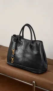 Detalle de la textura de piel negra del bolso tote con elegantes cierres dorados