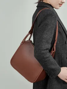 Classic brown pebble leather tote bag with metallic studs for a minimalist commuting look