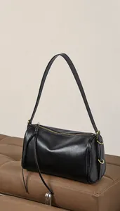 Détail du sac polochon en cuir noir minimaliste avec finitions dorées et slogan épuré