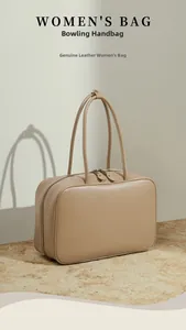 Detailed view of a beige genuine leather bowling handbag with double zipper and handles