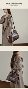 Detalle del bolso tote de cuero marrón oscuro con hebillas doradas y correa