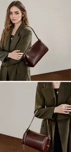 Détail d'un sac cylindre en cuir marron foncé avec fermetures éclair dorées et blazer vert