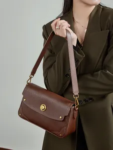Sac bandoulière en cuir marron rétro avec fermoir doré et rivets sur un mannequin