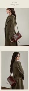 Détail d'un sac Boston en cuir marron foncé avec pompon et fermeture éclair métallique