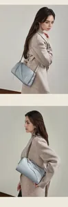 Vue détaillée du sac boston bleu clair en cuir porté en bandoulière sur un manteau
