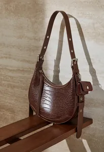 Detail of dark brown leather crescent bag with crocodile texture and detachable mini pouch