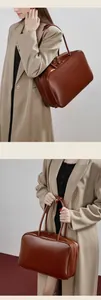 Detail shot of brown leather bowling bag shown in shoulder and hand-carry style