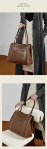 Detail van donkerbruine leren tote bag met decoratieve stiksels en zijritsaccent
