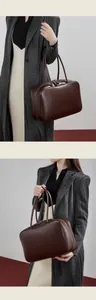 Detail of a vintage dark brown leather bowling bag with top handles and smooth texture