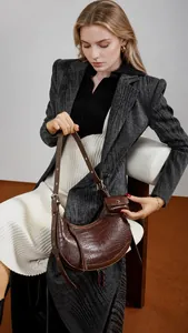Brown crocodile pattern half-moon bag with adjustable strap and mini pendant on model